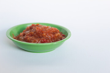 Portrait of tomato chili sauce in a green bowl isolated on a white background.