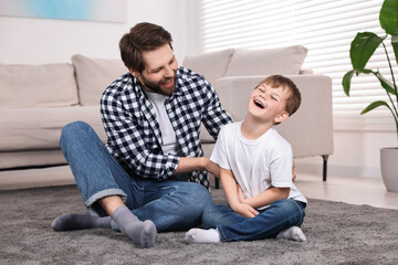 Happy dad and son having fun on carpet at home