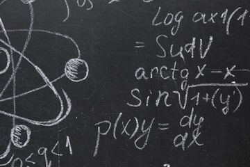 Many different physical formulas written with chalk on blackboard