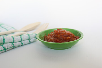 Portrait of tomato chili sauce in a green bowl isolated on a white background.