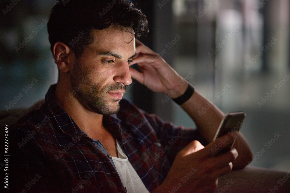 Poster Man, phone and night in office at startup with reading, texting and communication on web in overtime. Person, smartphone and thinking for notification, networking and scroll on app at creative agency