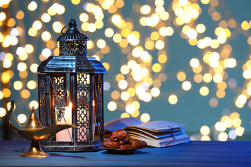 Arabic lantern, Quran, dates and Aladdin magic lamp on table against light blue background with...