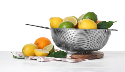 Metal colander with citrus fruits on table against white background