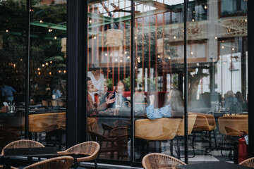Group of friends having a lively discussion while enjoying coffee in a trendy cafe. Captured through the window, the scene reflects a cozy and lively setting.