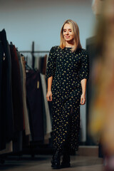 Woman Wearing a Long Floral Dress in Fashion Store. Trendy girl trying on different styles in a...