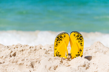 Yellow Sandal rubber shoe on the beach vacation time to travel. Tropical summer beach with sea wave...