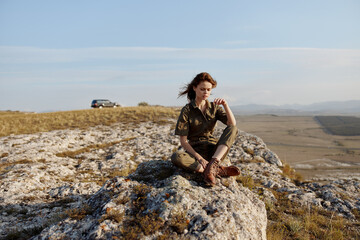 Woman sitting on rock in field with car in background, travel adventure beauty art inspired trip happiness nature enjoyment_pathway