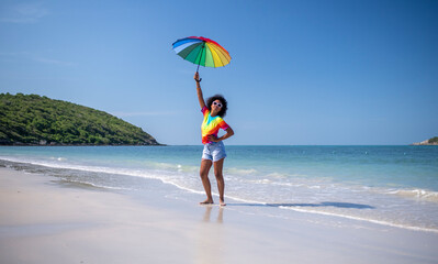 Happiness woman smiles and jumping relaxed summer holiday on ,rainbow t-shirt and rainbow umbrella symbol equality freedom of love friendship and LGBTQ concept.