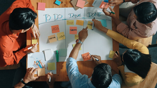 Top view of people writing and making scrum task board while writing marketing and planning strategy at colorful sticky notes. Smart team manage work performance by using kanaban board. Convocation.