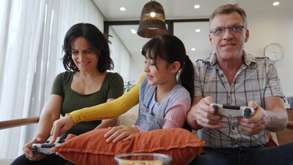 Grandfather, grandmother and granddaughter play console game as hobby. Old senior use technology...