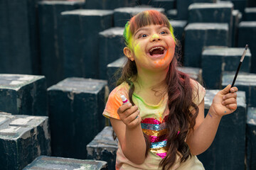 Beautiful little girl with Down syndrome painting on canvas outdoors in a sandbox in a public park...