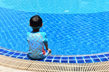 cute boy sit on the swimming pool, happy child