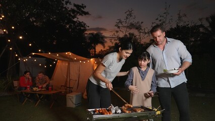 Family celebrate holiday in garden, Mother and child grill food for family member. Outdoor camping...