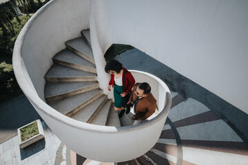 Professional businesspeople descending a spiral staircase outdoors, showcasing teamwork and...