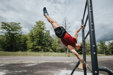 A fit man exercises on a park's outdoor fitness structure under a cloudy sky, demonstrating...