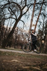 Fototapeta premium A young male teenager spends leisure time cycling outdoors surrounded by trees and nature, portraying a sense of freedom and joy.