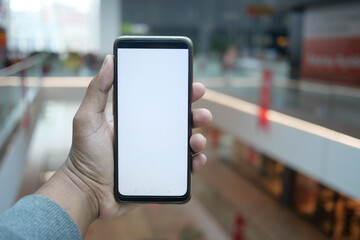 holding smart phone with empty screen against shopping mall background 