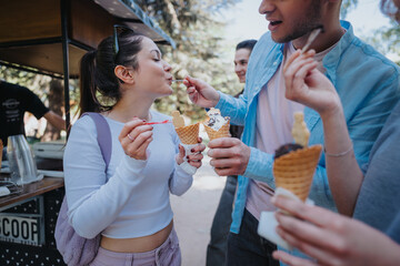 A lively scene of young adults sharing and enjoying ice cream cones at a park, depicting joy and...