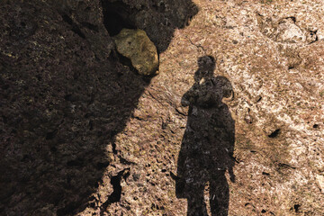 rocks on the beach ; shadow of a person in the rocky background ; silhouette of a man in the beach