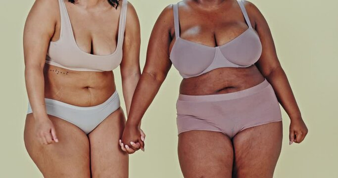 Holding hands, plus size body or happy women in underwear in studio isolated on green background. Positivity, inclusion or friends in lingerie, beauty or support diversity of different girls together