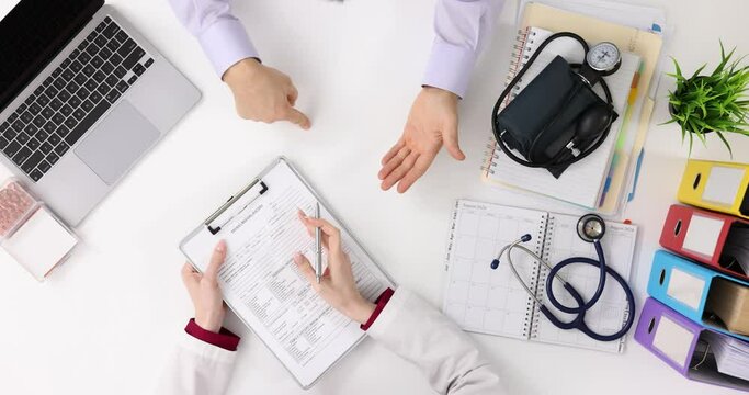 Doctor and patient discuss medical form, sign documents for treatment, medical care and prescription, top view