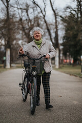 Obraz premium Mature woman with bicycle standing in the park, enjoying nature and an active lifestyle during the fall season.