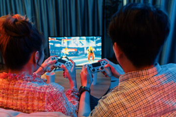 Couple gamer with controlled joystick playing fighting competition video game together on tv screen...