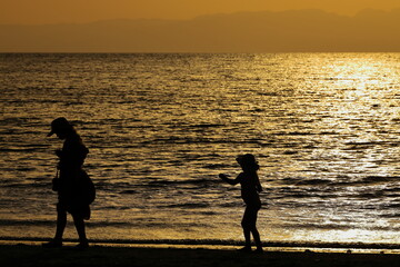 夕暮れの逗子海岸、仲良く散歩する親子のシルエット