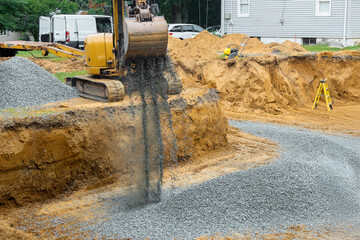 Excavators fill irregularities in excavations with granite rubble bases that will serve as...