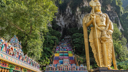 Many tourists climb the rainbow colored stairs to the entrance of the Batu cave. In the foreground...