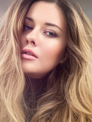 Obraz premium Beautiful modern blonde woman with volume hairstyle, long luxurious hair and beauty makeup, glamorous look face portrait for luxury fashion and natural cosmetics idea
