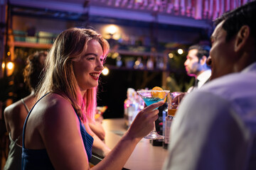 Beautiful young couple having fun, drinking alcohol cocktail in a bar. 