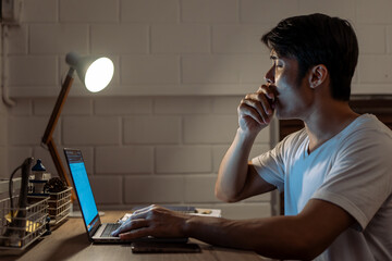 Asian fatigued young man overworking alone on working table at night.