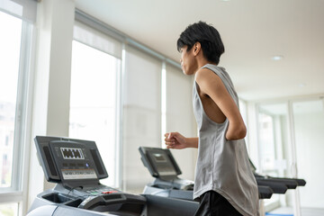 Asian young amputee without arm run on treadmill machine in fitness.