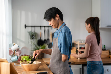 Asian young amputee without arm cooking foods with family in kitchen. 