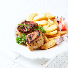 Fried pork ribs with french fries and fresh tomatoes. Bright background. Copy space.