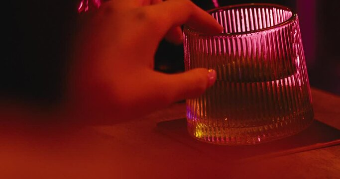 woman hands with long nail playing alone with a glass of whiskey in a bar cafe club