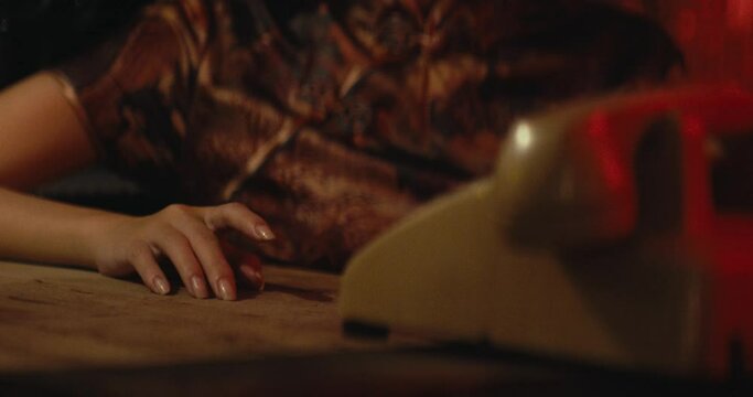 female hand finger knocking on table while waiting for a call from old vintage retro phone, wearing traditional asiatic chinese style dress