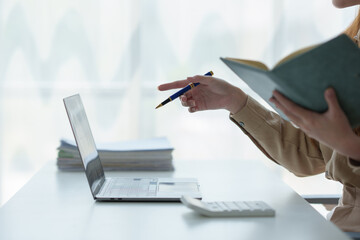 Fototapeta premium Young Asian woman looks happy wearing headphones Watch the webinar Listen to online courses Communicate with video conferencing and learn languages Laughing at teacher's lesson on laptop at desk.
