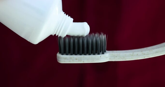 Closeup of a toothbrush applying white toothpaste
