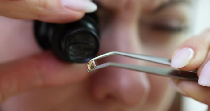 Closeup of a woman examining diamond with magnifying glass