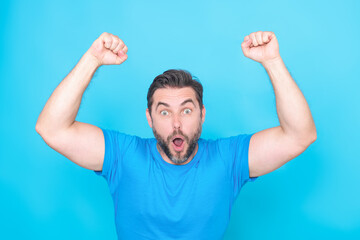 Cheerful excited man celebrating success over studio blue isolated background. Excited winner....