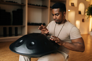 Closeup of meditated black male in trance practicing native music traditional drumming instrument...