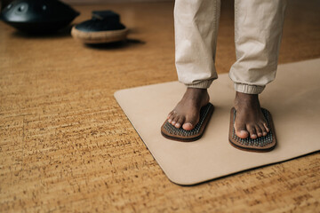 Closeup cropped shot of African-American man standing on wooden yoga Sadhu Board with metal nails...