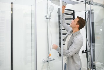 man choosing shower cabin and utensils for his home bathroom