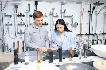 Couple choosing new sink faucet for their home in modern appliances store