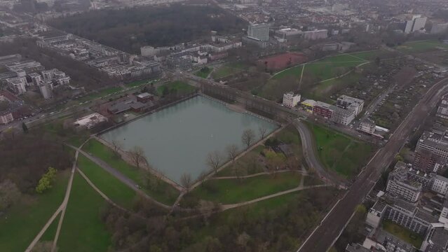 Green meadows around the Aachener Weiher in Cologne, Germany. View of public park, buildings, and urban infrastructure from aerial perspective