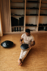 Full length vertical portrait of black drummer male in trance enjoying playing using drumsticks on...