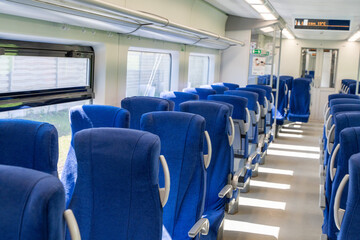 Traveling by train. The cabin of a modern train with blue seats without people. Selected focus