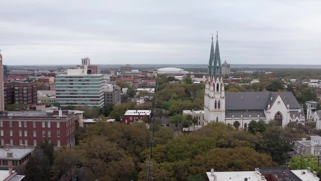 Low aerial shot flying over the famous city squares of Savannah, Georgia towards the Cathedral Basilica of Saint John the Baptist. 4K